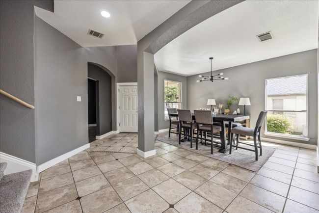 Dining room with arched walkways, a chandelier, visible vents, and light tile patterned floors | Image 5