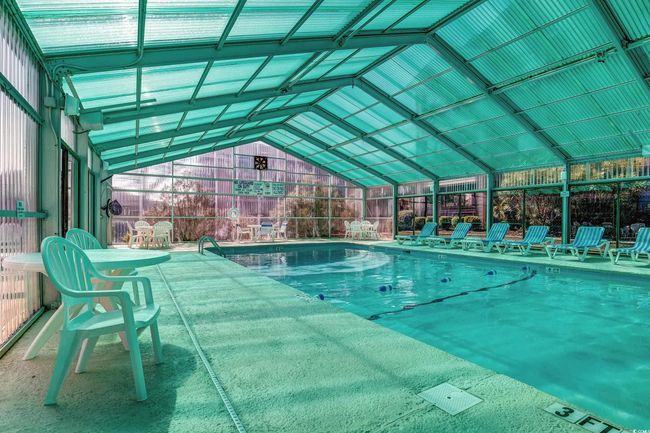 Indoor pool with a patio area and glass enclosure | Image 35