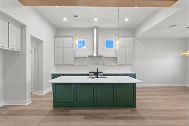 Kitchen featuring wall chimney range hood, pendant lighting, and white cabinets | Image 7