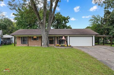 Ranch-style house featuring a garage, a front lawn, and a carport | Image 1