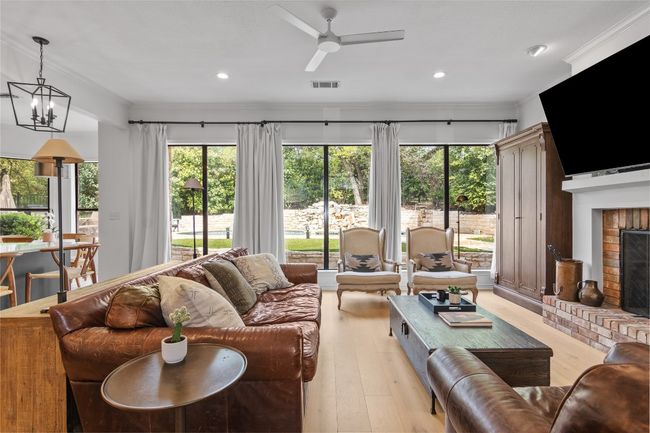 Living room featuring ceiling fan with notable chandelier, a wealth of natural light, visible vents, and a fireplace | Image 9