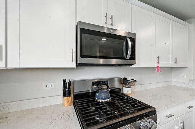 Kitchen featuring appliances with stainless steel finishes, white cabinetry, and light stone counters | Image 11