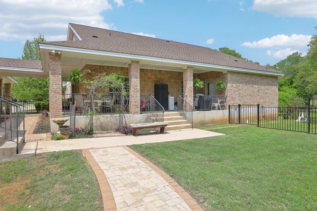 View of front facade with brick siding, a porch, fence, and a front lawn | Image 24