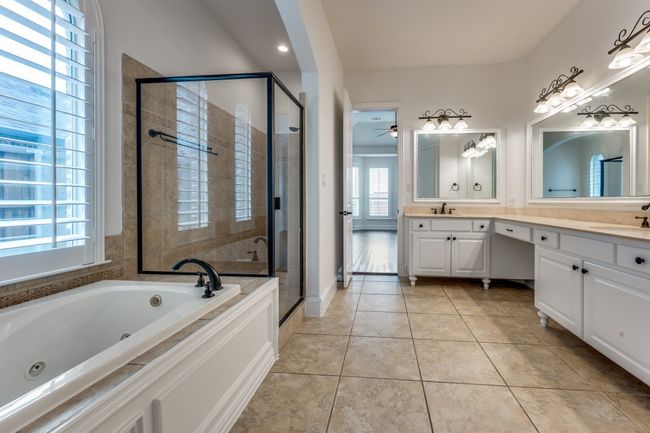Bathroom featuring tile patterned floors, a sink, a shower stall, and a tub with jets | Image 9