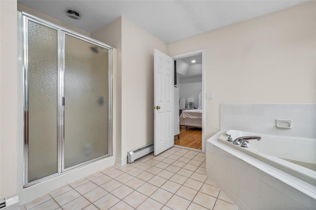Ensuite bathroom with a stall shower, tile patterned floors, a baseboard radiator, and connected bathroom | Image 27