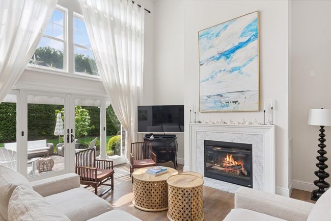 Living room with wood finished floors, french doors, a premium fireplace, and a high ceiling | Image 7