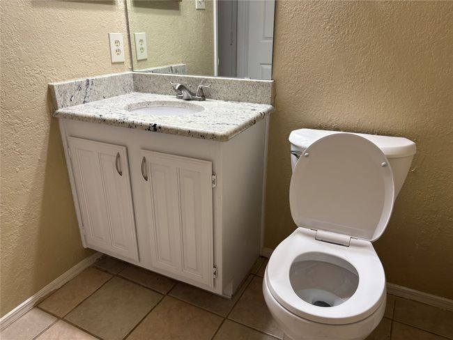 Bathroom featuring baseboards, toilet, and a textured wall | Image 13