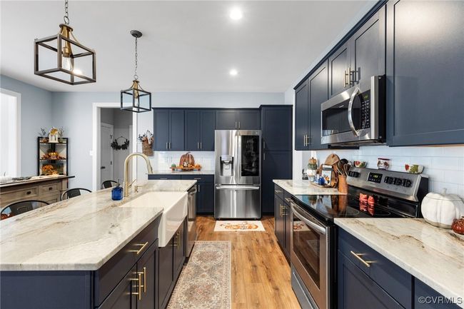 Kitchen featuring tasteful backsplash, light stone countertops, a sink, light wood finished floors, and stainless steel appliances | Image 4