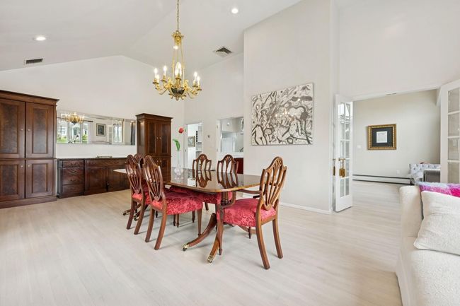 Dining area with a chandelier, high vaulted ceiling, baseboard heating, light wood-style floors, and baseboards | Image 10