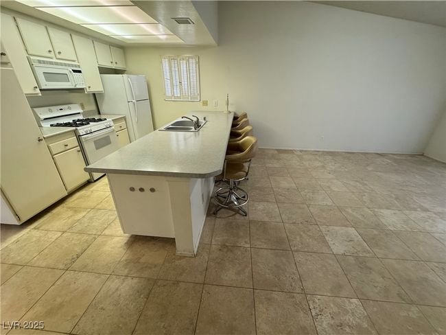 Kitchen featuring white appliances, a kitchen bar, a peninsula, and light countertops | Image 41