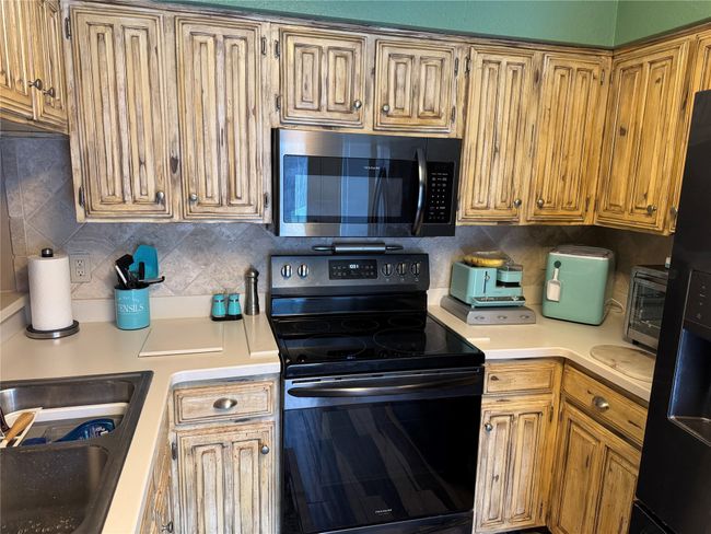 Kitchen featuring electric range, light countertops, and decorative backsplash | Image 6