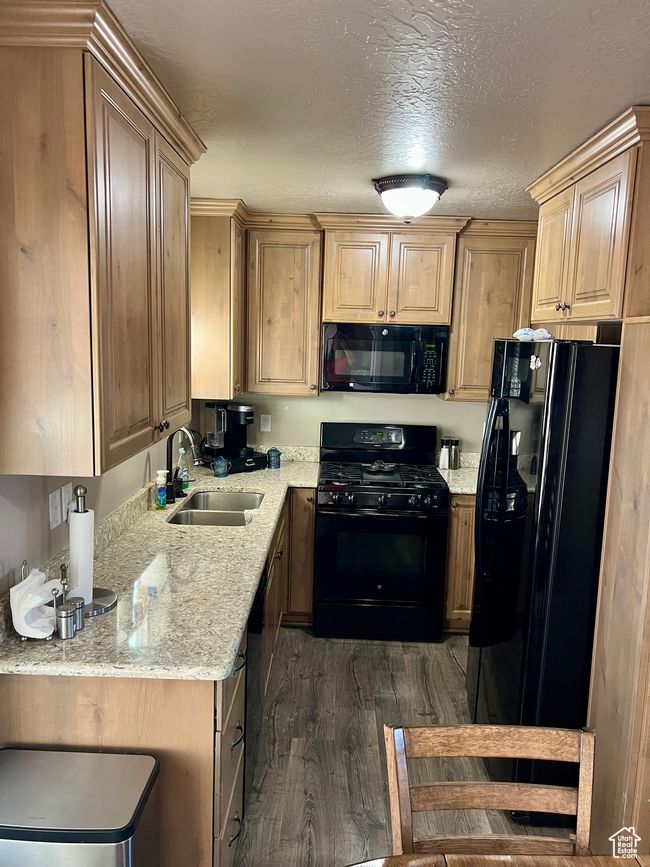 Kitchen with black appliances, dark wood finished floors, light stone counters, and light brown cabinetry | Image 25