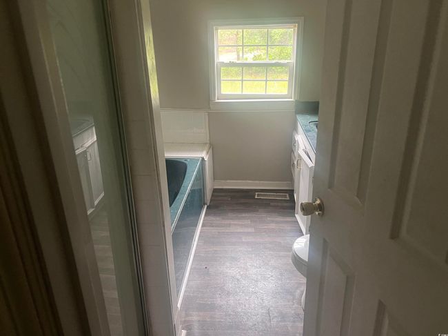Bathroom featuring vanity, toilet, a garden tub, wood finished floors, and baseboards | Image 8