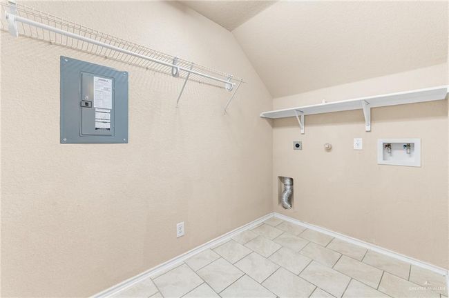 Laundry area with electric panel, electric dryer hookup, hookup for a washing machine, gas dryer hookup, and light tile patterned floors | Image 18
