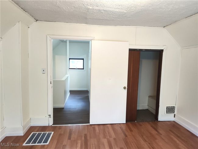 Unfurnished bedroom with wood finished floors, lofted ceiling, a textured ceiling, and baseboards | Image 40