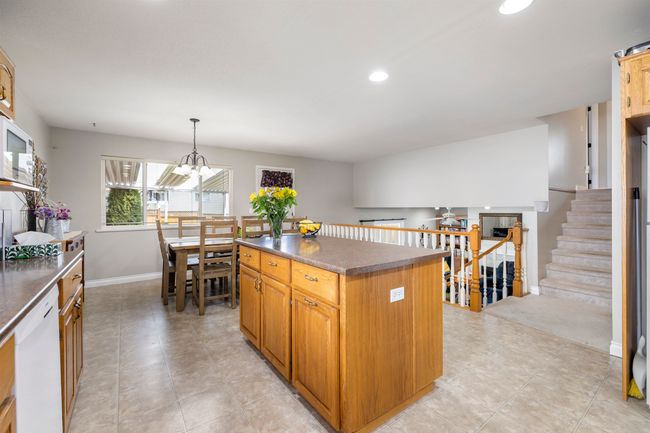 Kitchen featuring an inviting chandelier, dark countertops, white dishwasher, a center island, and baseboards | Image 10