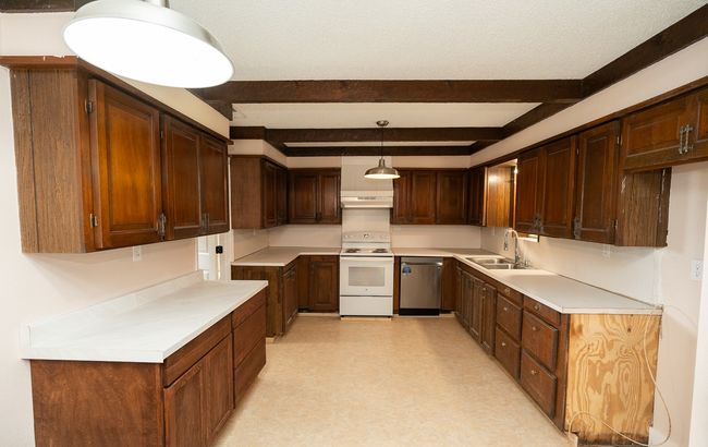 Kitchen featuring electric range, dishwasher, beam ceiling, light floors, and under cabinet range hood | Image 13