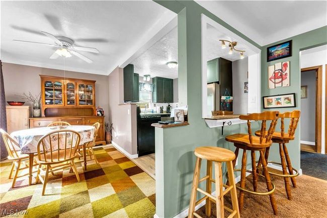 Kitchen with green cabinets, dishwasher, a breakfast bar area, a ceiling fan, and light floors | Image 9