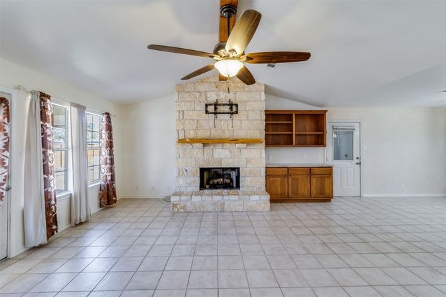 Unfurnished living room with baseboards, lofted ceiling, light tile patterned flooring, a fireplace, and ceiling fan | Image 8