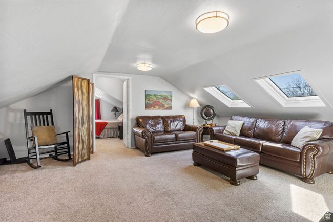 Carpeted living area featuring lofted ceiling with skylight | Image 10