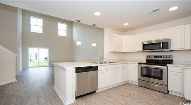 Kitchen with visible vents, a sink, stainless steel appliances, a peninsula, and light wood finished floors | Image 9
