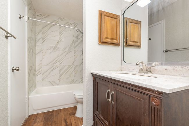 Bathroom with vanity, a textured wall, wood finished floors, and bathing tub / shower combination | Image 14