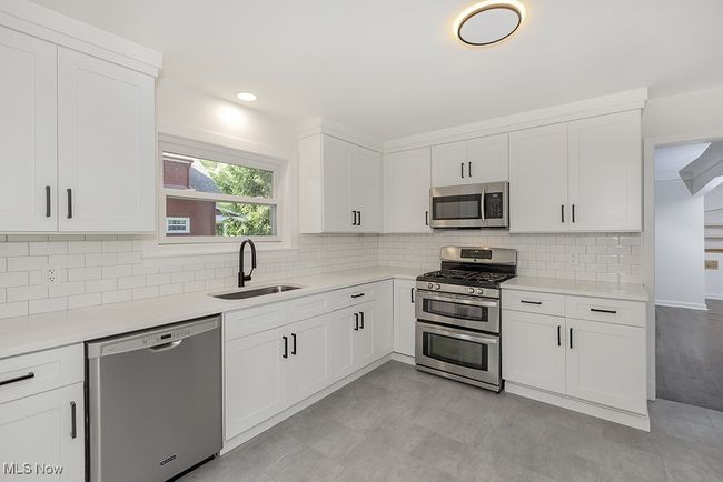 Kitchen with sink, appliances with stainless steel finishes, light hardwood / wood-style flooring, decorative backsplash, and white cabinetry | Image 16