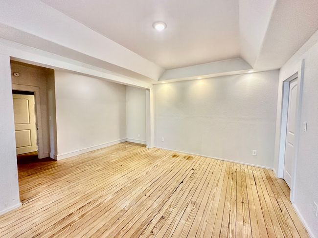 Empty room featuring wood-type flooring and a tray ceiling | Image 12