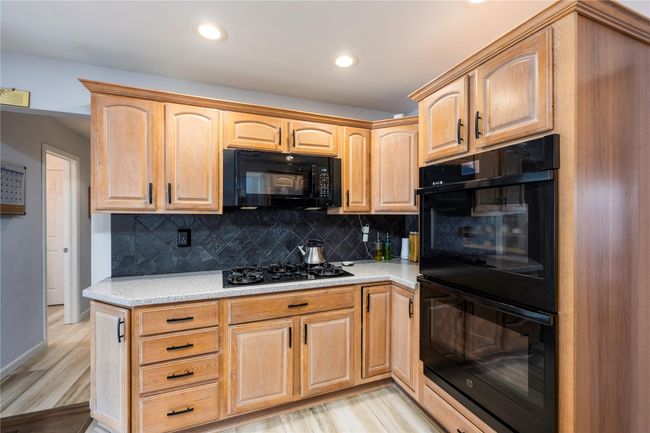 Kitchen with light stone countertops, sink, a fireplace, and black appliances | Image 5