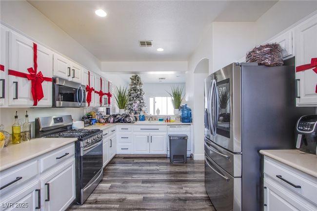 Kitchen featuring appliances with stainless steel finishes, white cabinetry, light countertops, dark wood-type flooring, and recessed lighting | Image 4