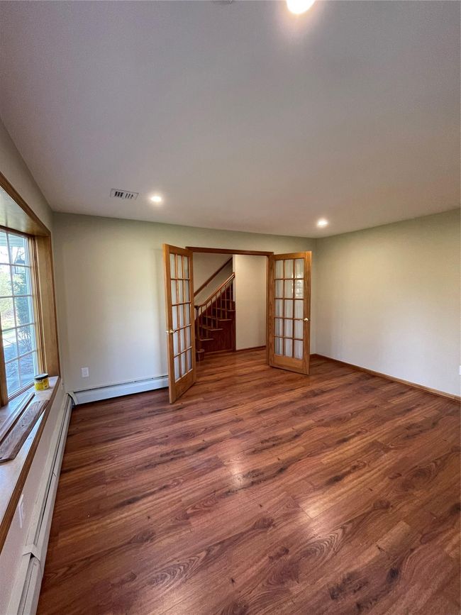 Unfurnished dining room featuring a baseboard heating unit, stairs, french doors, and wood finished floors | Image 4