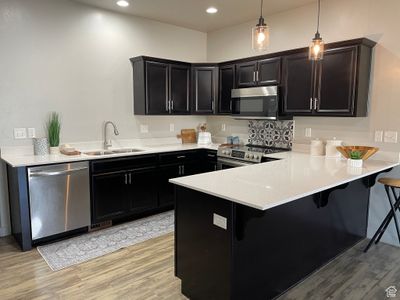 Kitchen featuring new quartz countertop, new pendant lights, a new sink, and stainless steel appliances. | Image 1