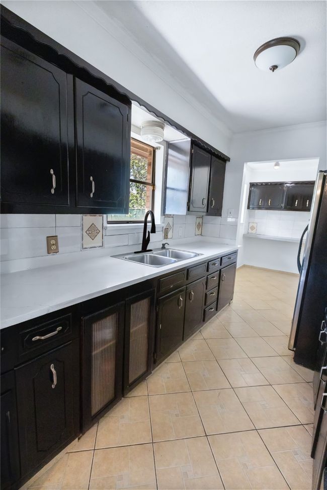 Kitchen featuring sink, backsplash, ornamental molding, and light tile patterned floors | Image 5