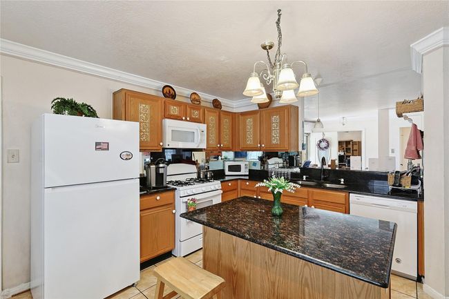 Kitchen features granite countertops, stainless steel appliances, and rich wood cabinetry — all in a bright, well-maintained space. Refrigerator included, making this home move-in ready. | Image 8