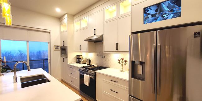 Kitchen featuring a sink, light countertops, white cabinets, under cabinet range hood, and stainless steel appliances | Image 24