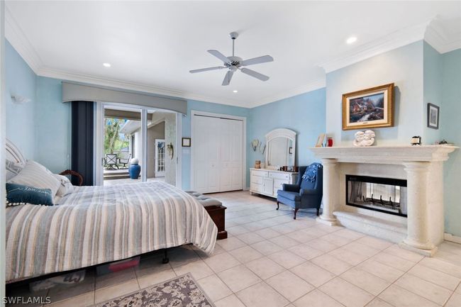 Bedroom with light tile patterned flooring, crown molding, a multi sided fireplace, and ceiling fan | Image 17