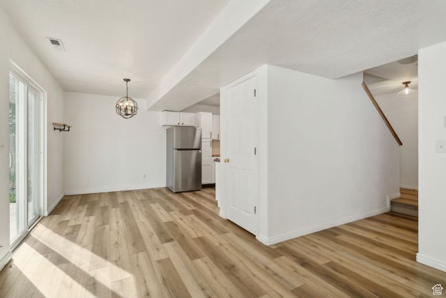 Unfurnished dining area with light wood-type flooring, a chandelier, and baseboards | Image 6