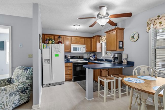 Kitchen with white appliances, a sink, a peninsula, brown cabinets, and light wood finished floors | Image 10