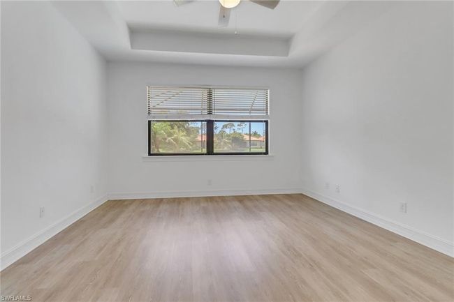 Unfurnished room featuring a tray ceiling, light wood-style floors, a ceiling fan, and baseboards | Image 16