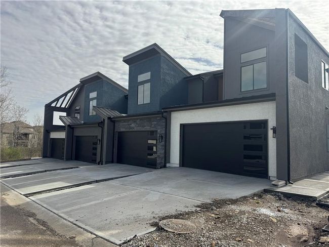 View of property exterior with concrete driveway, a standing seam roof, stucco siding, and an attached garage | Image 4