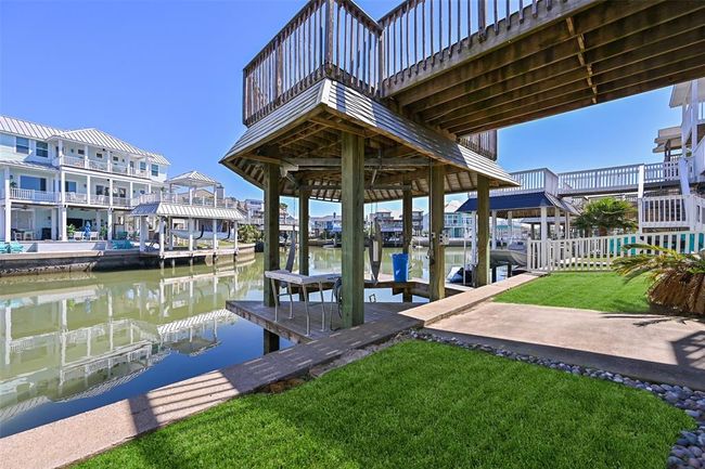 Back yard lawn with a covered boat slip and lift for effortless waterfront living. | Image 26