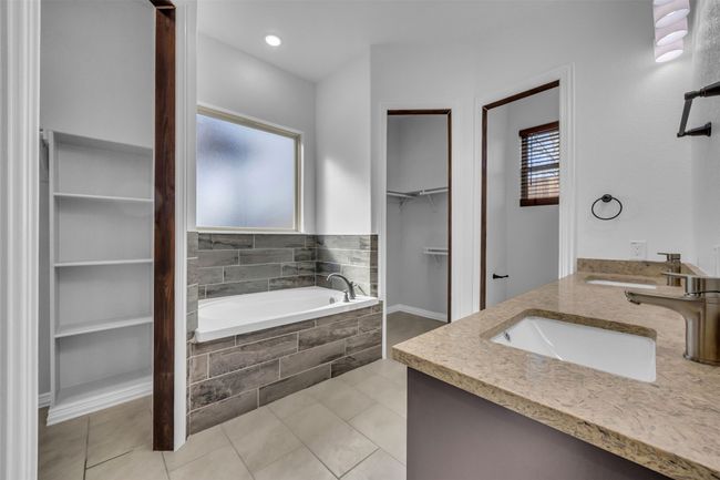 Bathroom featuring tiled tub, vanity, and tile patterned floors | Image 18