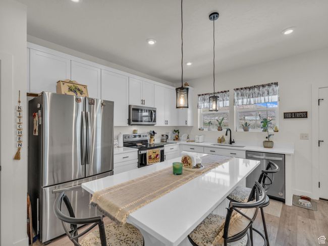Kitchen featuring stainless steel appliances, a sink, a kitchen breakfast bar, recessed lighting, and light countertops | Image 8