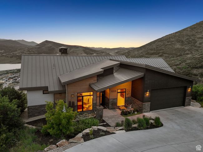 View of front of home with a standing seam roof, stone siding, an attached garage, and concrete driveway | Image 80