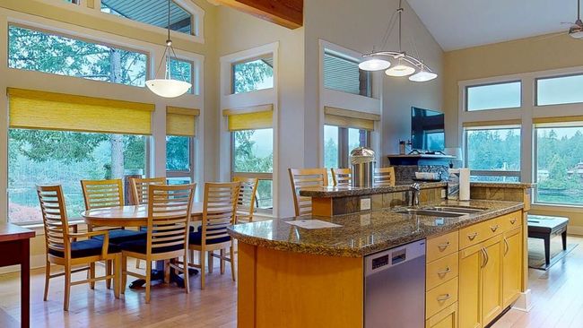 Kitchen featuring light wood finished floors, dishwasher, an island with sink, high vaulted ceiling. | Image 5