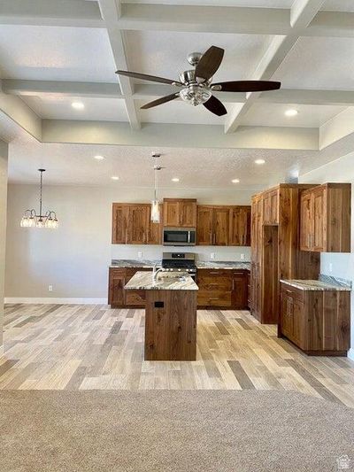 Kitchen with an island with sink, light stone countertops, appliances with stainless steel finishes, and light hardwood / wood-style floors | Image 3