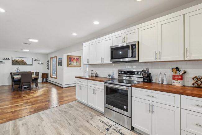 Kitchen with tasteful backsplash, light wood-type flooring, appliances with stainless steel finishes, and butcher block counters | Image 15