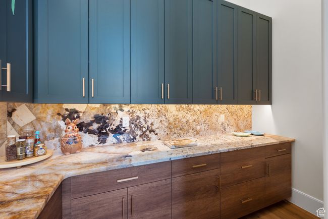 Kitchen with blue cabinetry, tasteful backsplash, light stone countertops, and wood finished floors | Image 34
