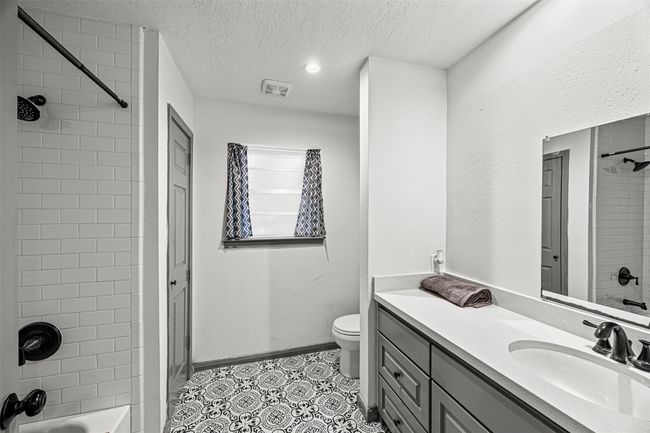 Bathroom includes a large vanity with dual sinks, a framed mirror, and ample storage space, complemented by patterned floor tiles. | Image 24