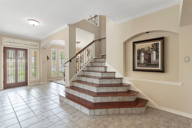 Welcoming entry with grand staircase, arched openings, and abundant natural light. | Image 5